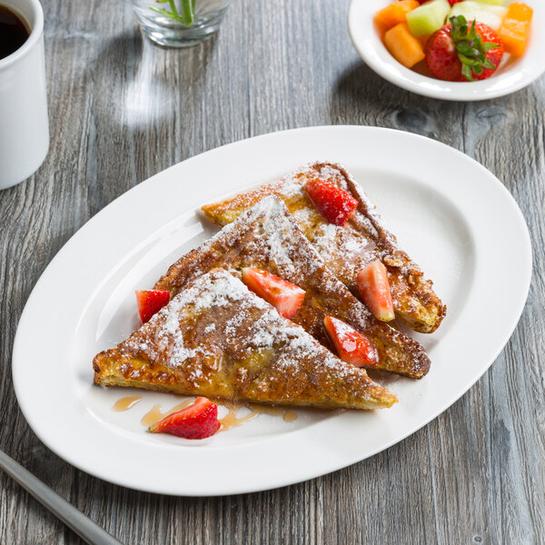 A white Libbey oval platter with french toast, strawberries, and syrup.