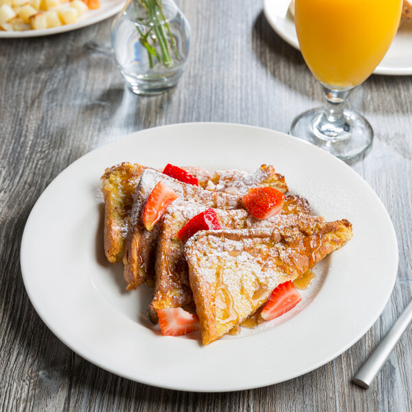 A close up of a Libbey white porcelain plate with French toast, strawberries, and syrup.