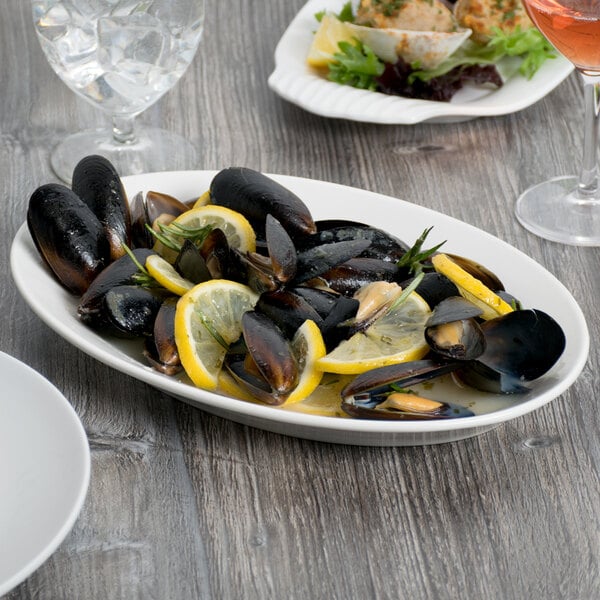 A white Libbey oval porcelain platter with mussels and lemon slices.