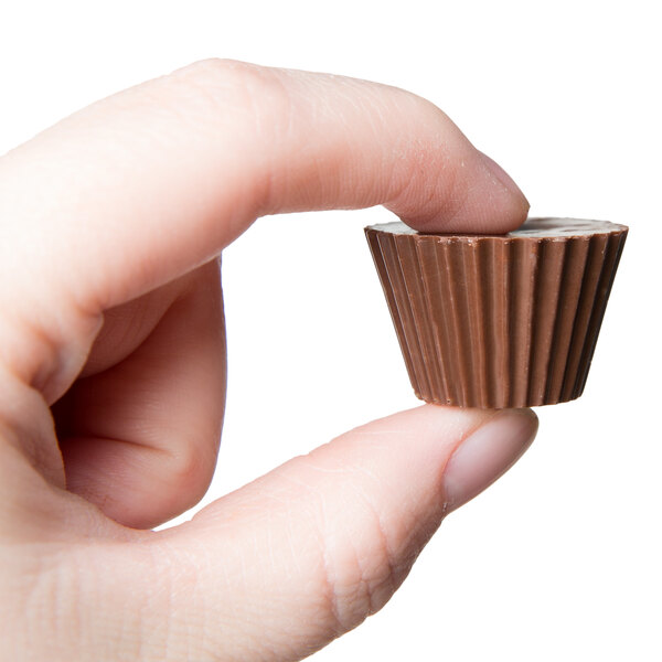 A hand holding a small chocolate cup made with a Chocolate World Polycarbonate chocolate mold.