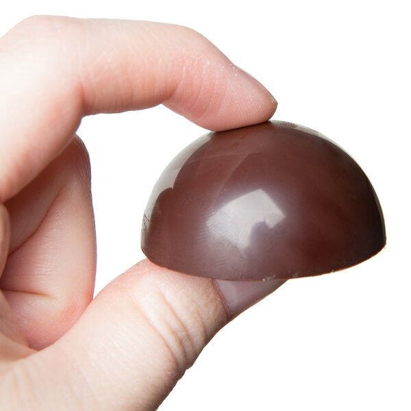 A hand holding a Matfer Bourgeat large chocolate half sphere