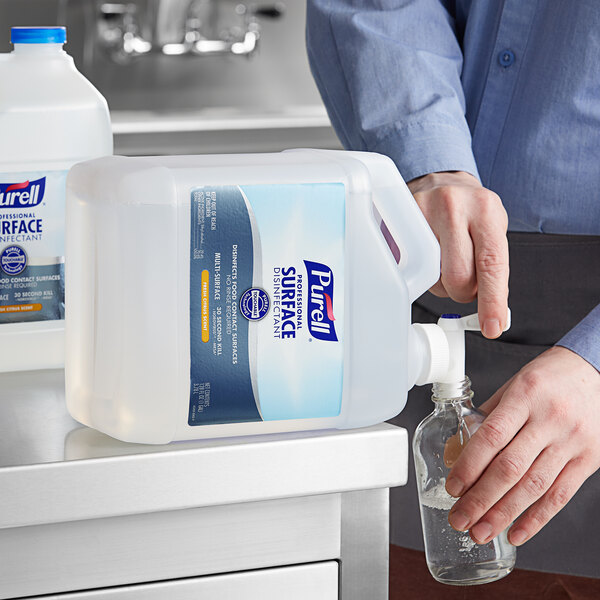 A person pouring Purell Fresh Citrus Disinfectant from a plastic bottle.