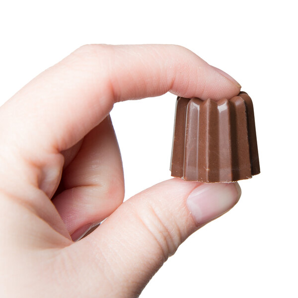 A hand holding a small chocolate candy made with a Matfer Bourgeat 40 compartment candy mold.