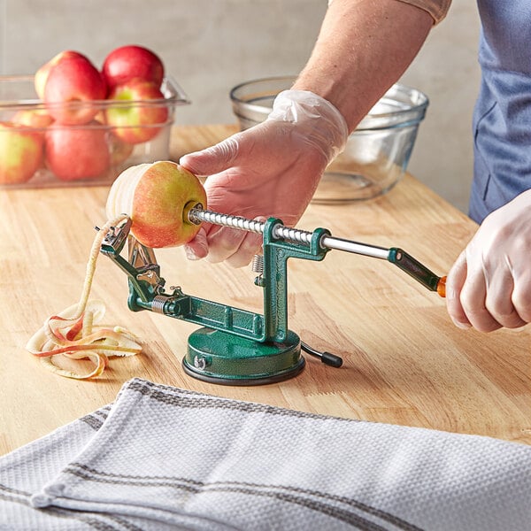 A person using a Choice Cast-Aluminum Apple Slicer / Peeler / Corer to peel a red apple.