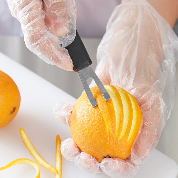 A person using a Victorinox channel knife to cut an orange.