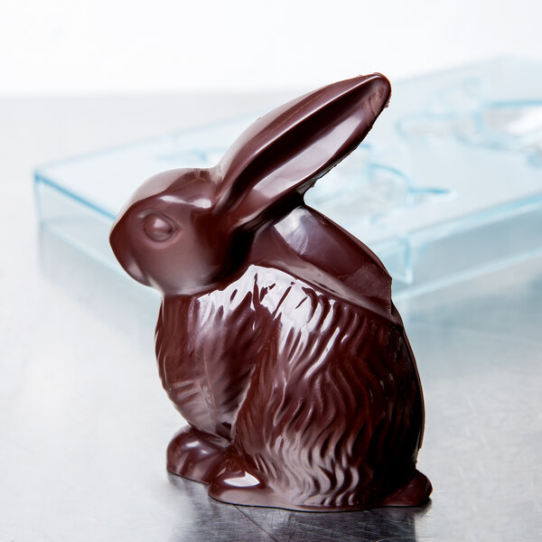 A Matfer Bourgeat polycarbonate chocolate mold with a rabbit-shaped chocolate sitting on a white table.