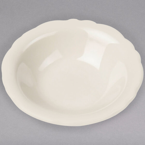A white Homer Laughlin Carolyn fruit bowl with a scalloped edge on a gray surface.