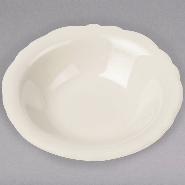 A white Homer Laughlin bowl with a small scalloped edge on a gray surface.