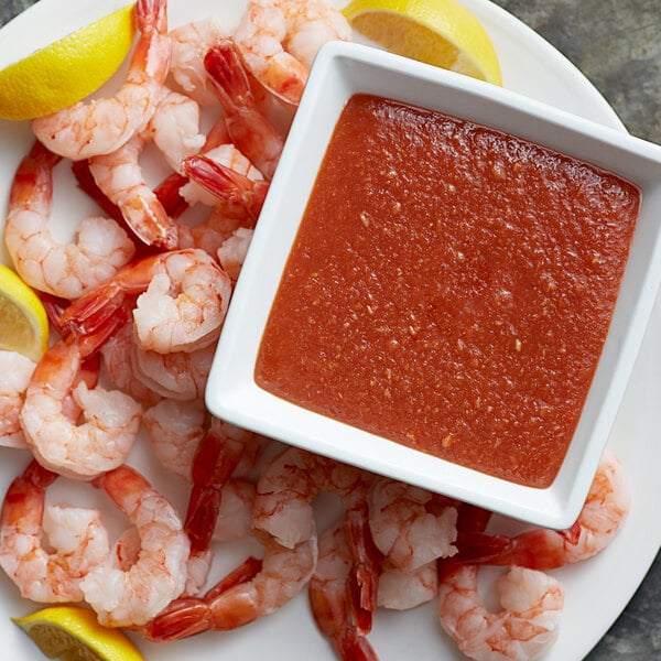 A plate of shrimp with Tulkoff Seaside Cocktail Sauce on a white plate with a lemon wedge.