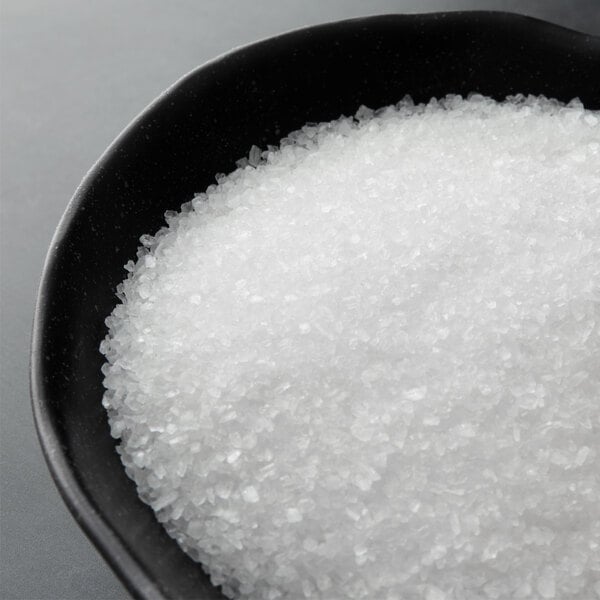 A bowl of Regal Coarse Sea Salt on a black surface.