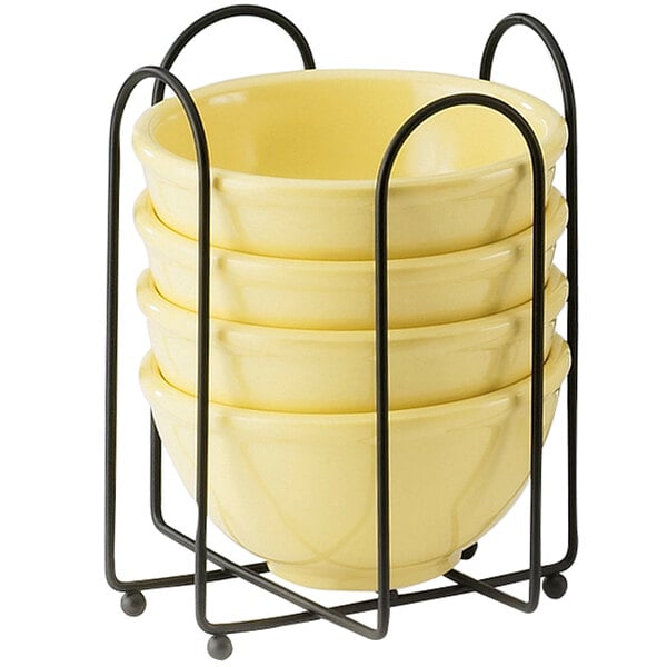 A stack of yellow bowls in a metal plate and napkin holder.