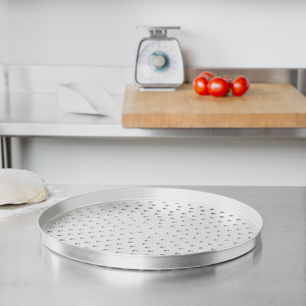 An American Metalcraft tin-plated steel pizza pan with perforated sides on a table.