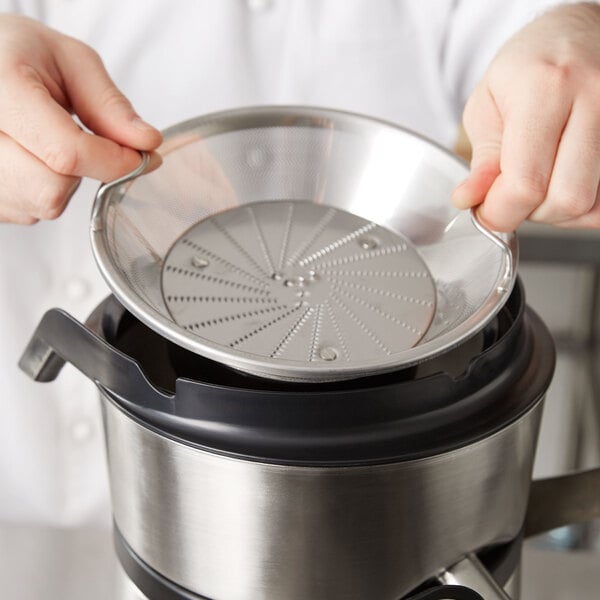 A hand using an AvaMix filter basket to juice into a cooking pot.