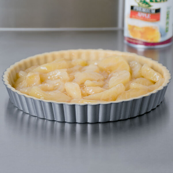 A pie with apples in it in a Wilton fluted quiche pan on a counter.