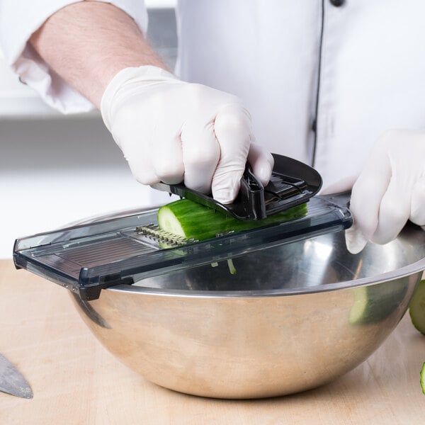 A person using a Mercer Culinary Julienne Hand Slicer to cut a cucumber on a counter.