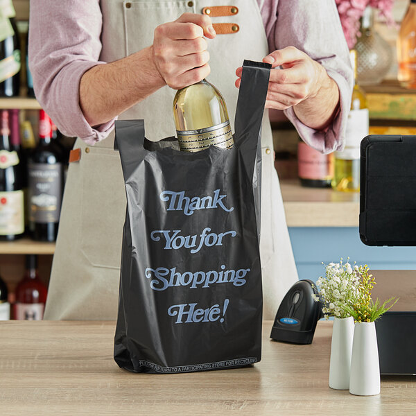 A man opening a bottle of wine in a black plastic bag with white text that reads "Thank You"