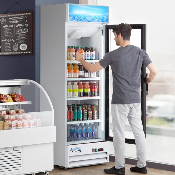 A man opening an Avantco white glass door refrigerator filled with drinks.