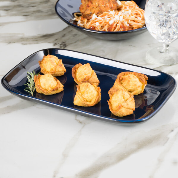 A blue GET Cosmo melamine rectangular platter with spaghetti and meatballs on a table.