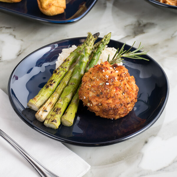 A GET Cosmo blue melamine plate with asparagus and meatballs on a white surface.