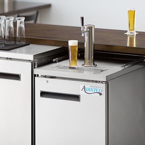 An Avantco stainless steel beer dispenser with a glass of beer on a counter.