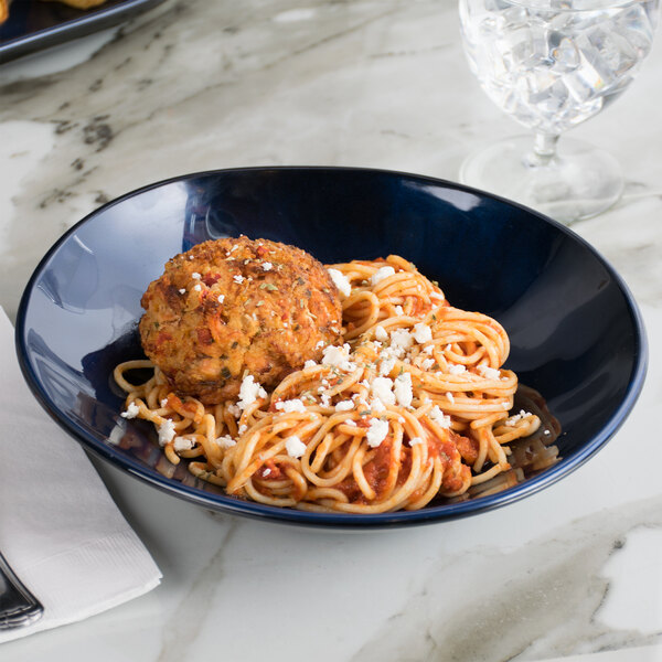 A blue GET Cosmo melamine bowl filled with spaghetti and meatballs on a marble table.