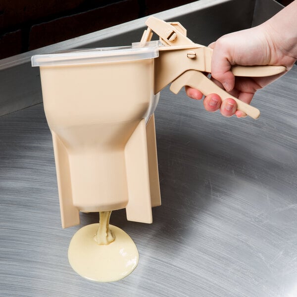 A hand using Vollrath batter boss to pour batter.