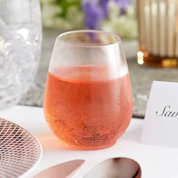 A Visions clear plastic stemless wine glass filled with wine on a table.