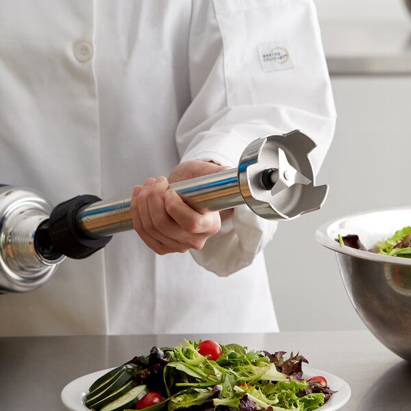 A person in a white coat using an AvaMix blending shaft to mix a salad.