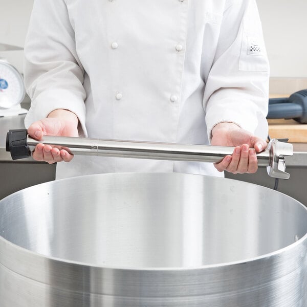 A person using an AvaMix heavy-duty blending shaft to blend in a large metal pot.