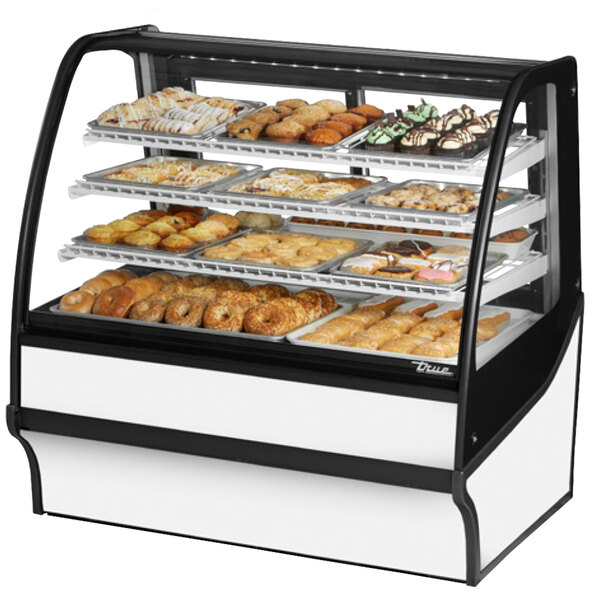 A True curved glass white dry bakery display case filled with various pastries.