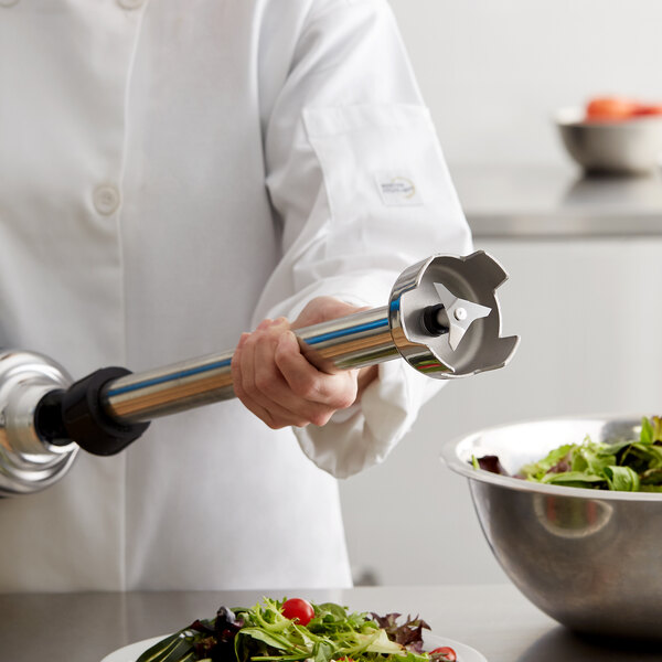 A person in a white coat using an AvaMix heavy-duty blending shaft to make a salad.