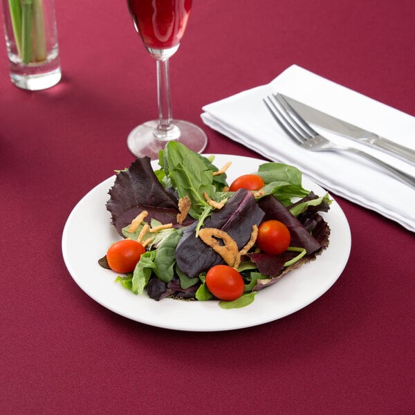 An Arcoroc Zenix glass salad plate with cherry tomatoes and greens.