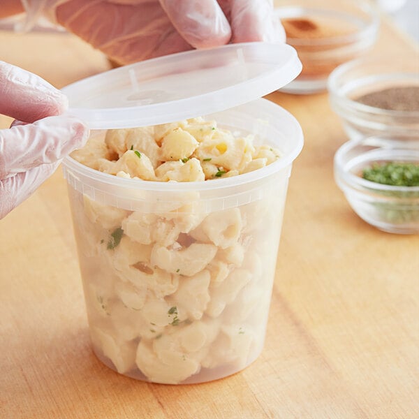 A gloved hand holds a Choice translucent plastic deli container of macaroni and cheese.