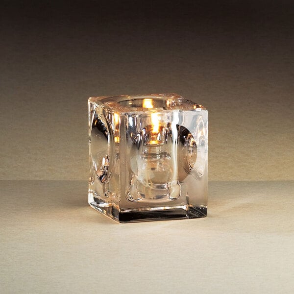 A Sterno Presidio Square glass candle holder with a lit candle inside.