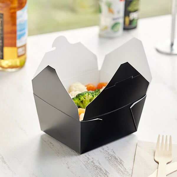 A black Choice microwavable paper take-out box with food inside.