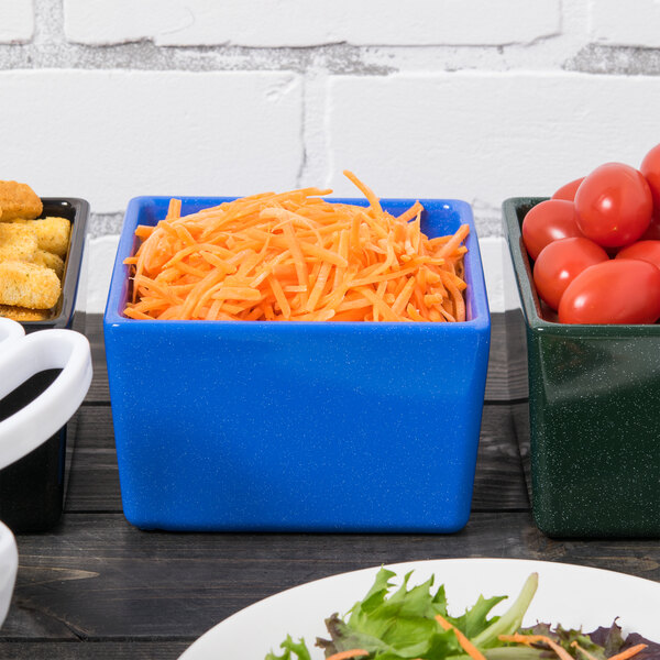 A blue Tablecraft Contemporary Collection bowl with shredded carrots in it on a table with other bowls of food.