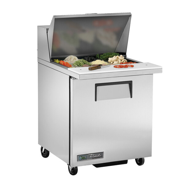 A True stainless steel refrigerated sandwich prep table with a food tray of vegetables on the counter.