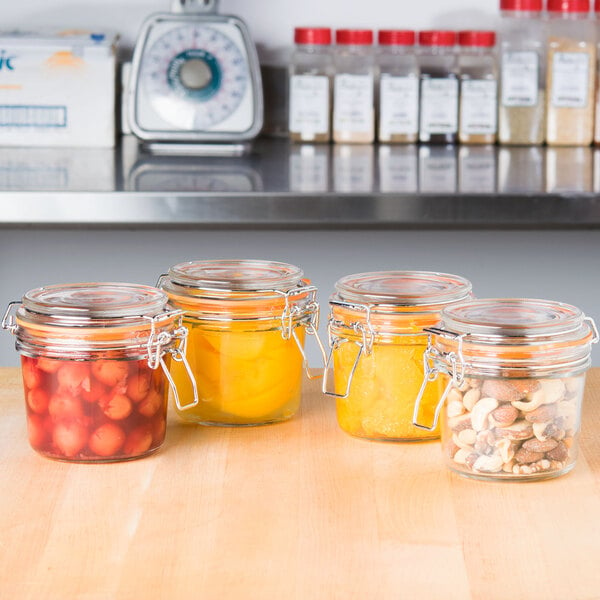 A group of Tablecraft glass condiment jars on a counter.