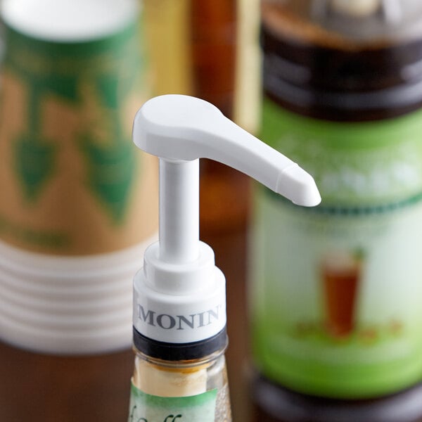 A white Monin pump on a bottle of syrup.