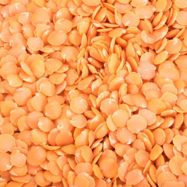 A pile of dried red lentils on a white background.