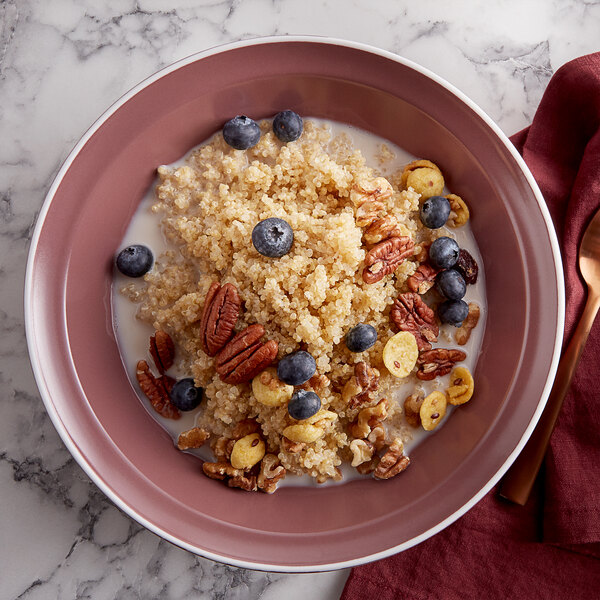 A white bowl of quinoa with blueberries and pecans.