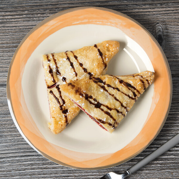 A Kanello ivory melamine plate with two pastries and chocolate and strawberry sauce on it.