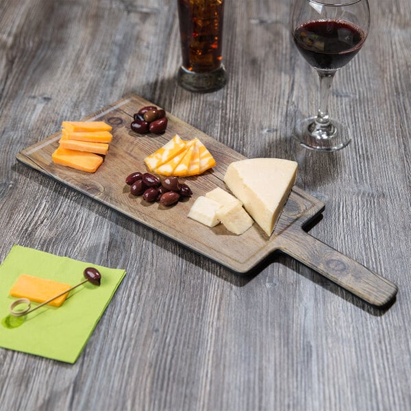 A GET Melamine faux oak wood display board with cheese, olives, and wine.
