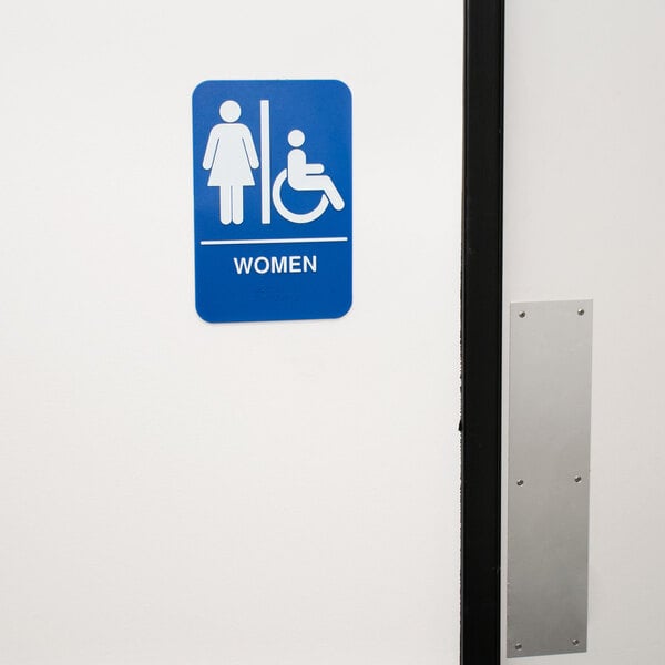 A blue and white Thunder Group ADA women's restroom sign with Braille on a white wall.