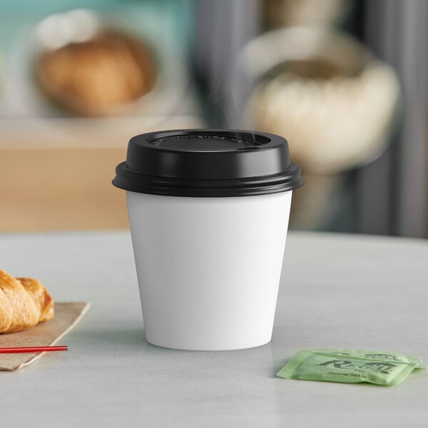 A white Choice paper hot cup with a black lid on a table.