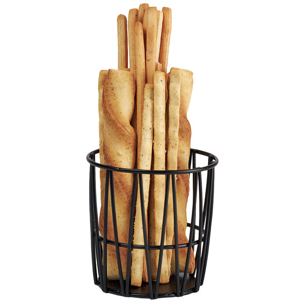 A Clipper Mill black iron powder coated basket filled with bread sticks.