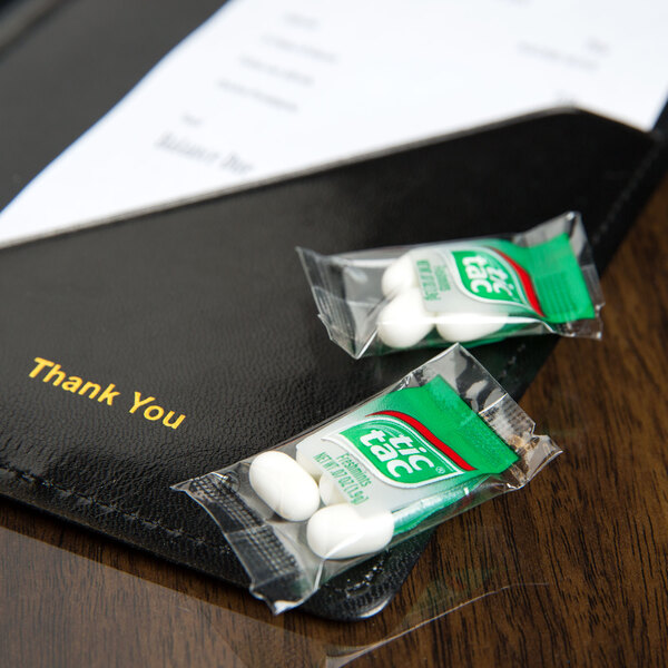 A Tic Tac mint pillow pack on a table with two mints.