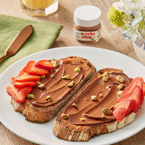Two pieces of toast with Nutella chocolate spread and strawberries on a plate.
