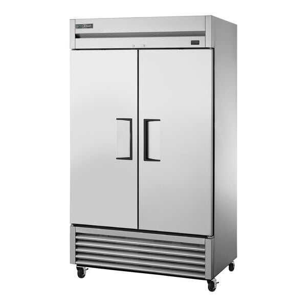 A large silver True reach-in freezer with two solid doors with black handles.