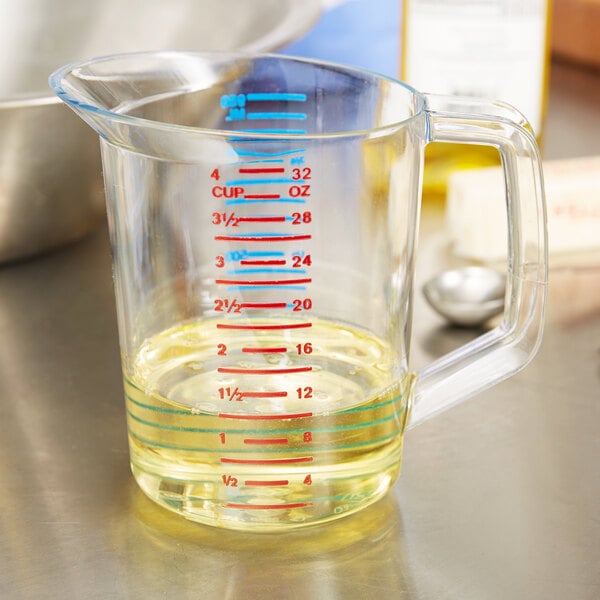 A Rubbermaid clear polycarbonate measuring cup on a counter with yellow liquid inside.